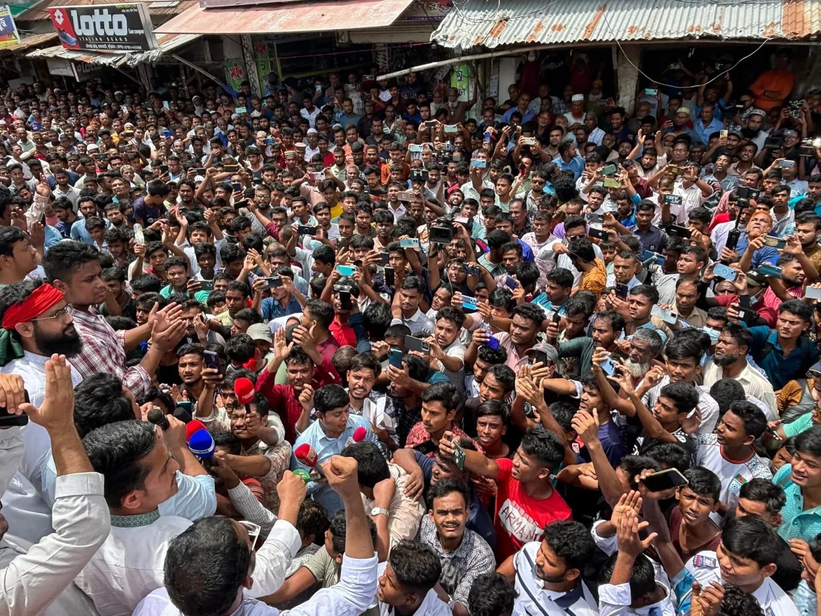 A vast crowd fills the streets during the July Uprising, hundreds holding up their phones